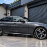 Šedé BMW 320d xDrive M Sport G20 z boku před garáží
