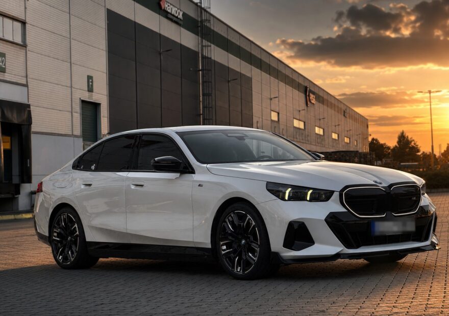 Bílé BMW i5 M60 xDrive G60 zepředu z boku při západu slunce