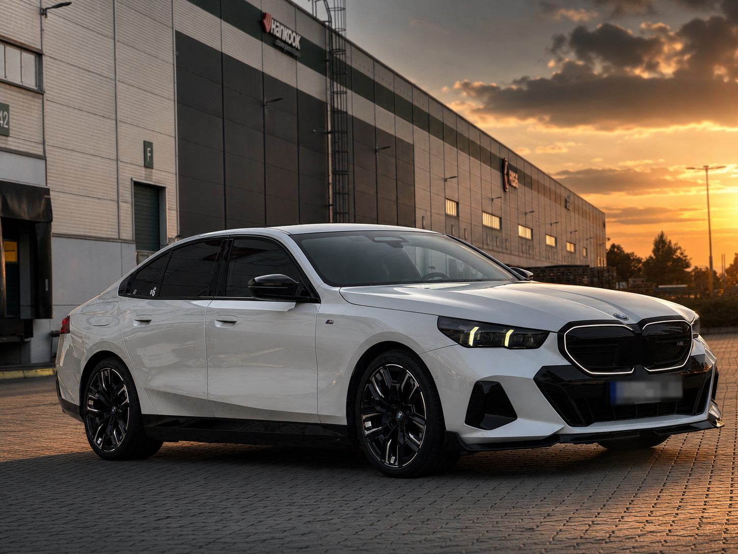 Bílé BMW i5 M60 xDrive G60 zepředu z boku při západu slunce