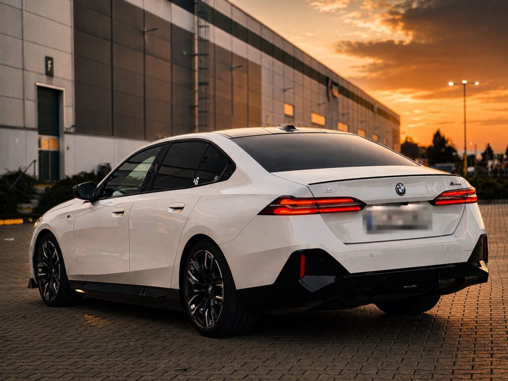Bílé BMW i5 M60 xDrive zezadu při západu slunce