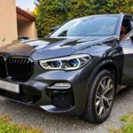 Šedé BMW X5 xDrive40i G05 zepředu z boku na příjezdové cestě