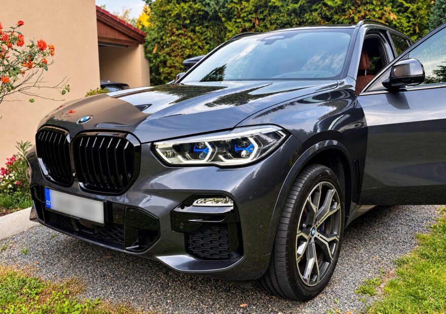 Šedé BMW X5 xDrive40i G05 zepředu z boku na příjezdové cestě