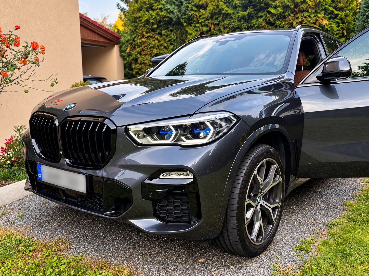 Šedé BMW X5 xDrive40i G05 zepředu z boku na příjezdové cestě