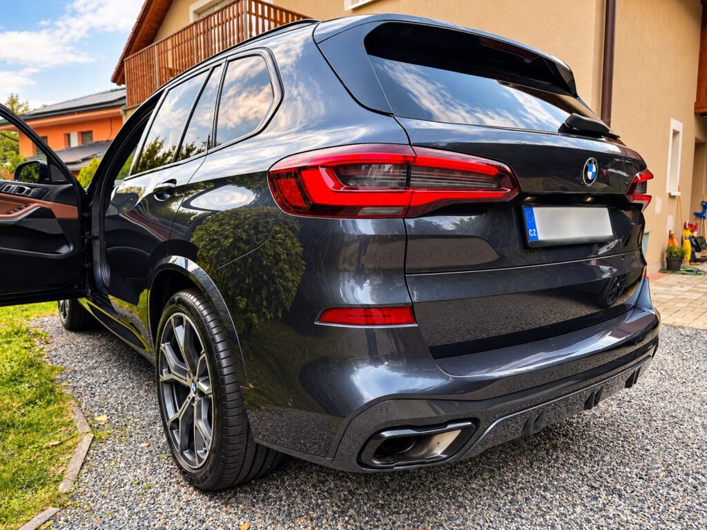 Šedé BMW X5 G05 zezadu z boku s otevřenými předními dveřmi