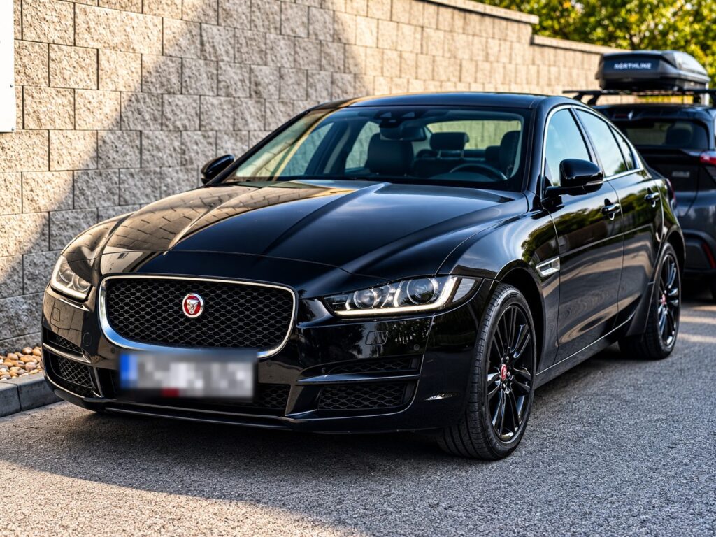 Černý sedan Jaguar zaparkovaný před zdí