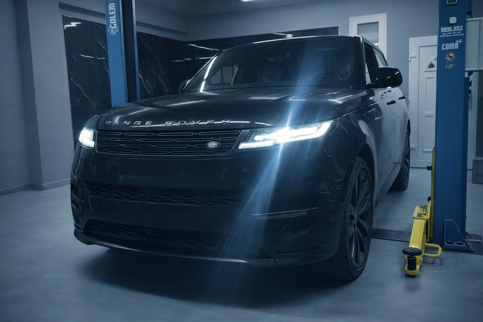 Černý Range Rover Sport s rozsvícenými světlomety v dílně